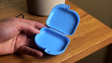 hand putting transparent dental teeth protector into carry case on wooden table