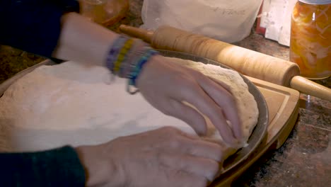 chef estirando la masa de pizza en una sartén para hornear