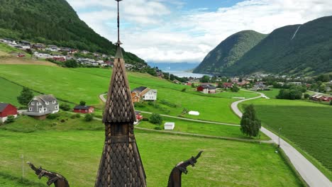 top of hopperstad stave church tower in vik sogn norway - aerial orbit with parallax and fjord view in background