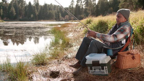 Hombre-Negro-Mayor-En-Un-Viaje-De-Campamento-Pescando-Junto-A-Un-Lago-Rural