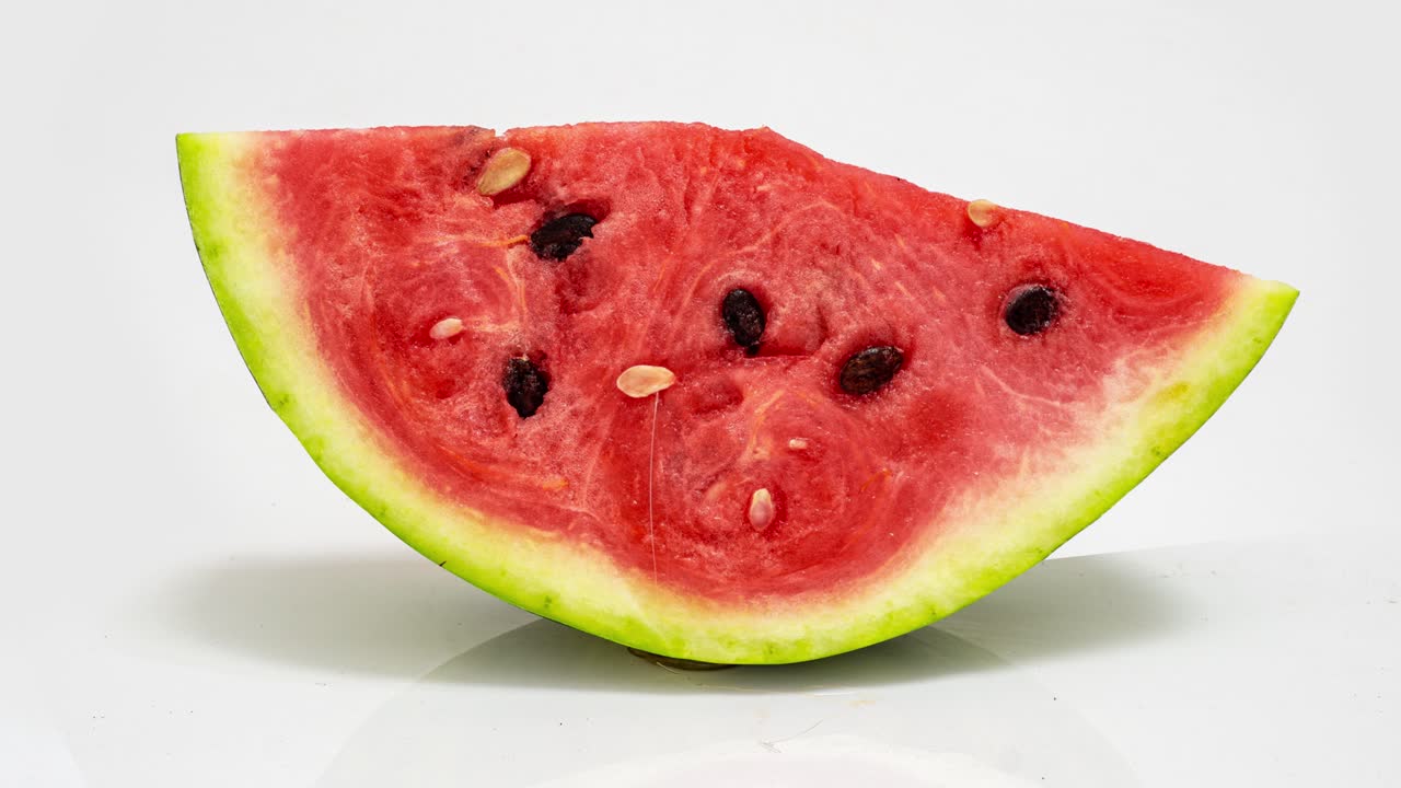 un pedazo de sandía madura podrida sobre un fondo blanco, lapso de tiempo, video cognitivo educativo