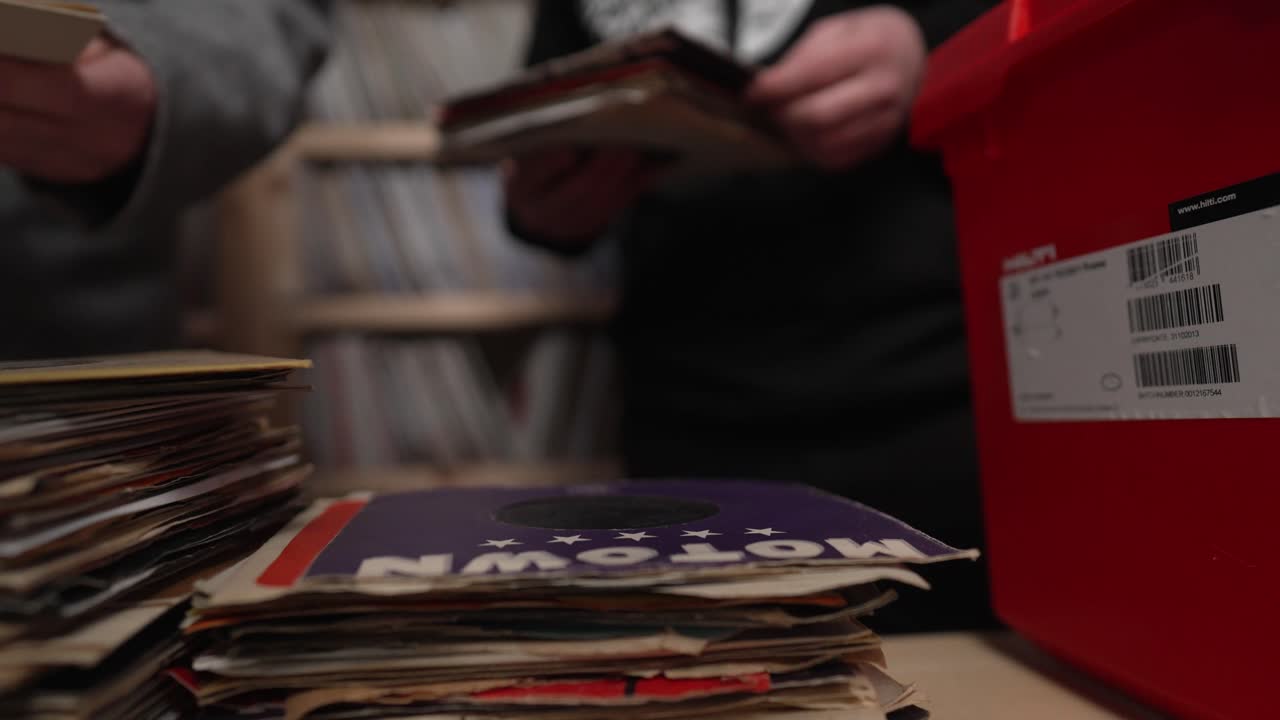 Two men immerse themselves in a cozy vinyl store, flipping through shelves of records, discussing their favorite artists, and uncovering rare gems