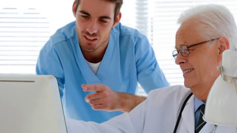médico interactuando con su colega mientras trabaja en la computadora