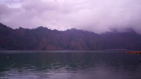 Lancha-Motora-Rápida-Pasa-Por-El-Lago,-Fondo-De-Montaña-Con-Nubes-Brumosas,-Kintamani-Bali,-Lapso-De-Tiempo