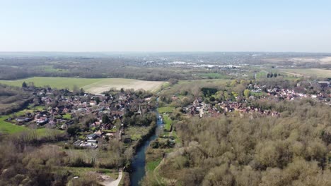 drone vuela hacia atrás sobre el bosque lejos del pequeño pueblo de fordwich, inglaterra