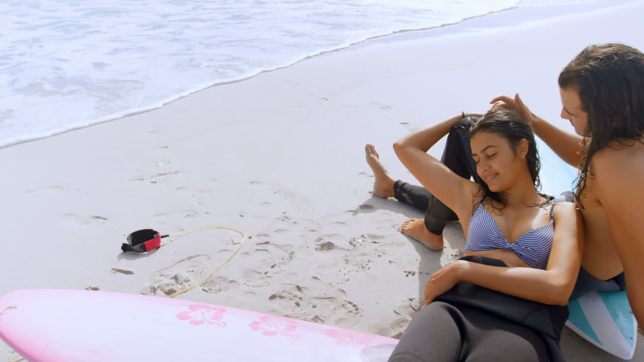 una pareja de surfistas relajándose en la playa 4k 4k