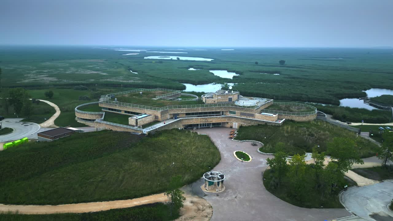 Foggy daytime hyperlapse shows eco modern centre amid green wetlands