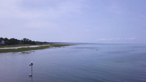 the camera pushes in and flies over the breakwater. you can see the vast expanse of the bay. seabirds can be seen flying through the frame, and people are walking the shoreline.