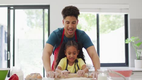 Happy-biracial-father-and-daughter-baking-together-in-kitchen