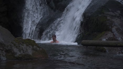 a man enjoying the natural waterfall spa massage - medium shot