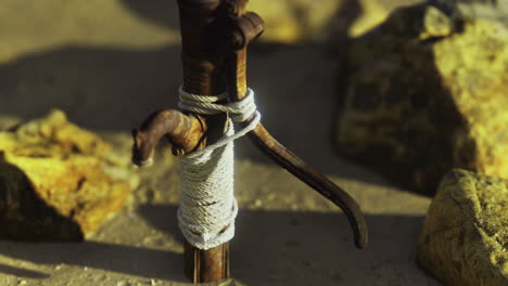 wooden stick secured with rope among rocks at a sandy location during daylight