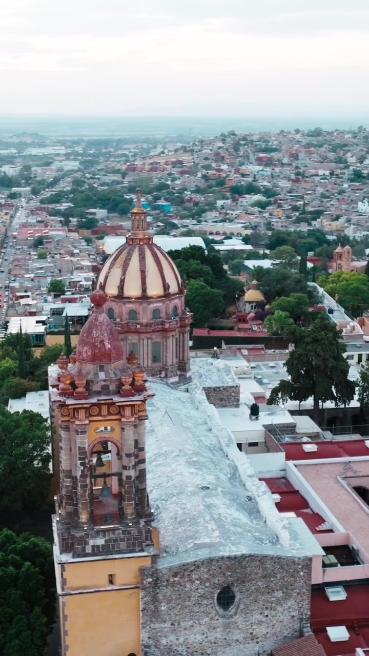 Tempio di San Francesco con cupola storica e campanile che si erge sopra il centro città di San Miguel de Allende, Guanajuato, Messico. Ripresa aerea orbitale verticale