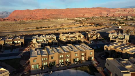 Moving-forward-above-houses-with-pool-and-horizon-of-mountains-and-desert-at-sunset