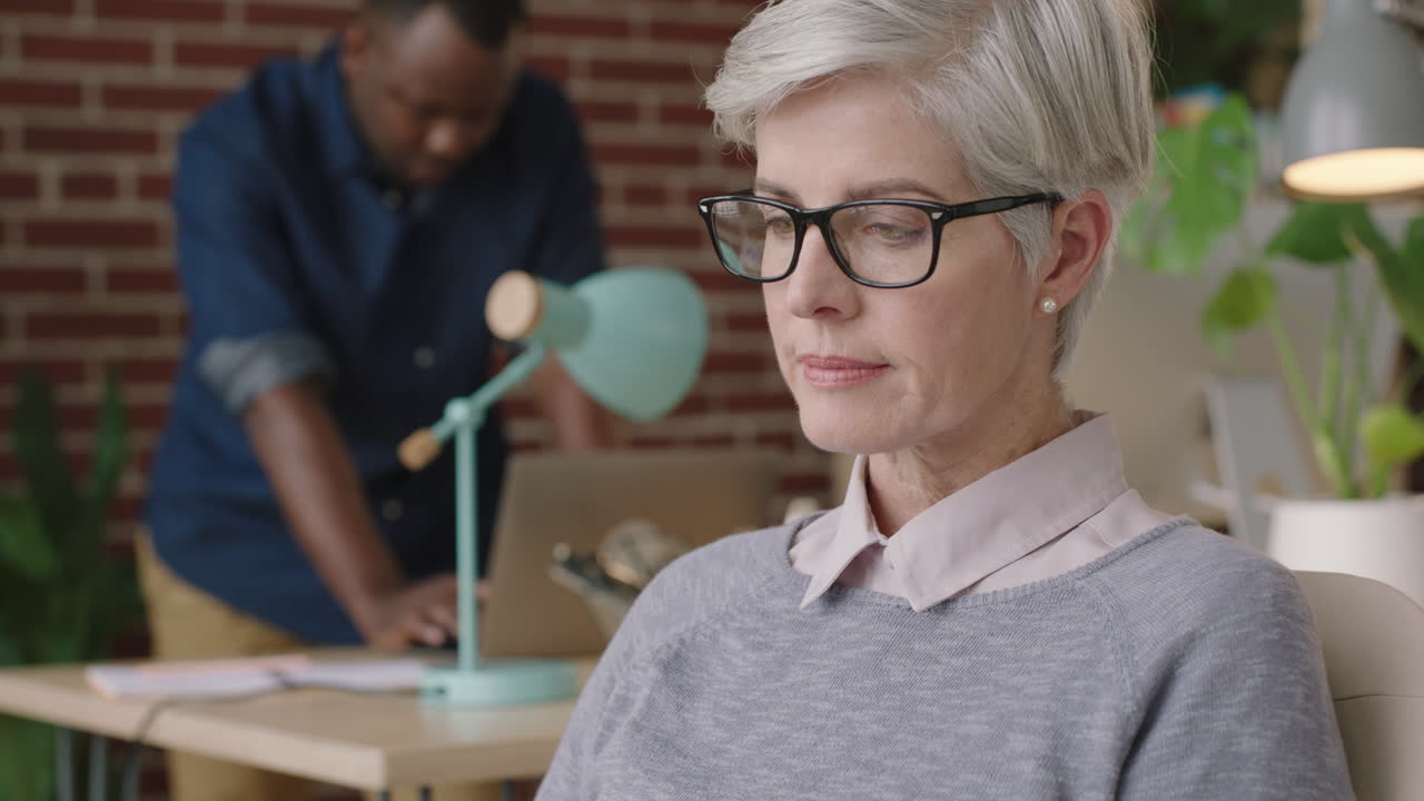 mature business woman puts on glasses looking relaxed reading in modern office workspace enjoying successful career milestone