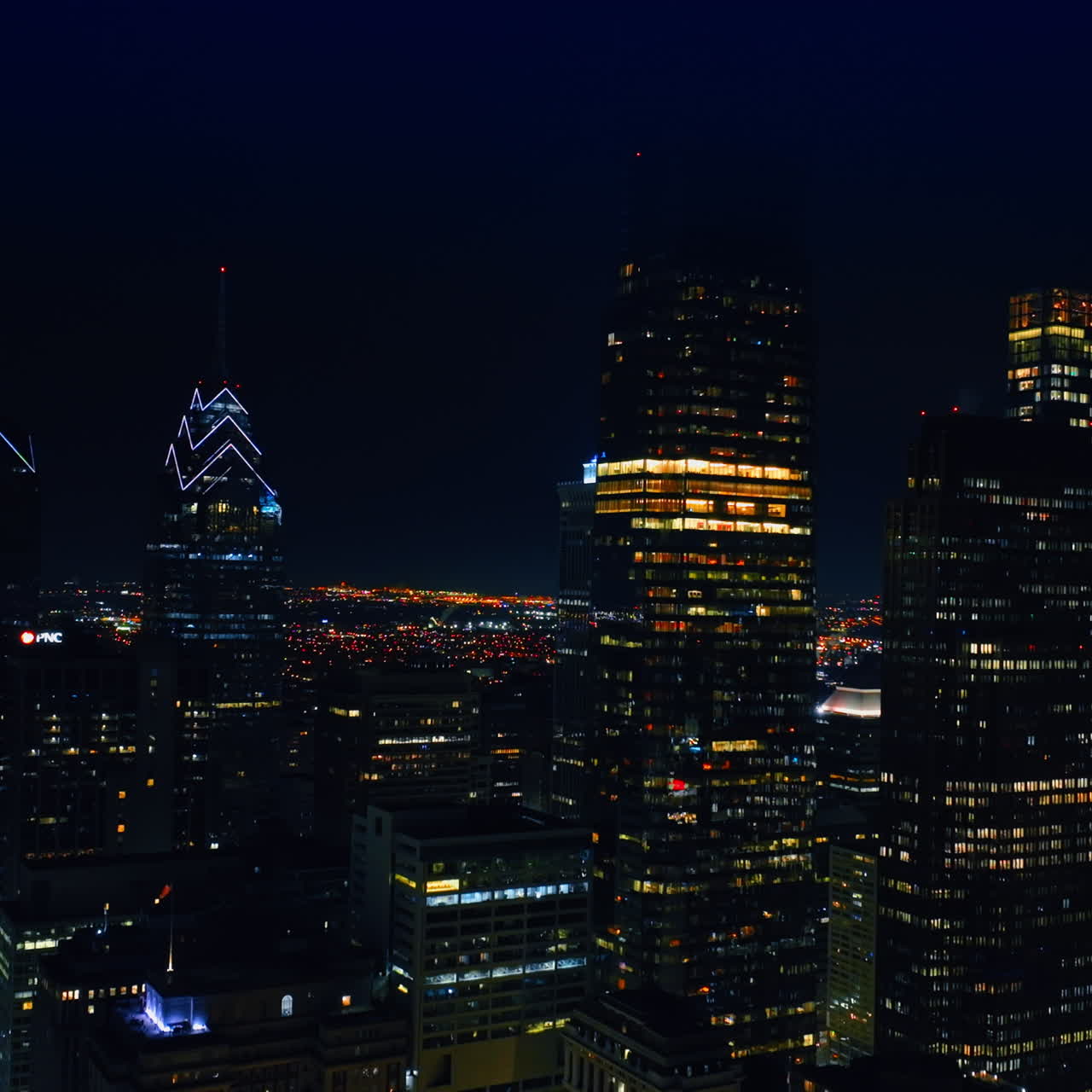 Rising along the skyscrapers with lights on in the windows. Night view of Philadelphia, Pennsylvania from drone.