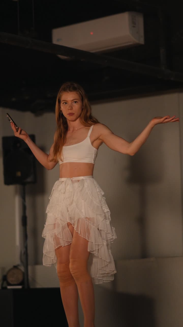 Donna in abito bianco che balla sul palco