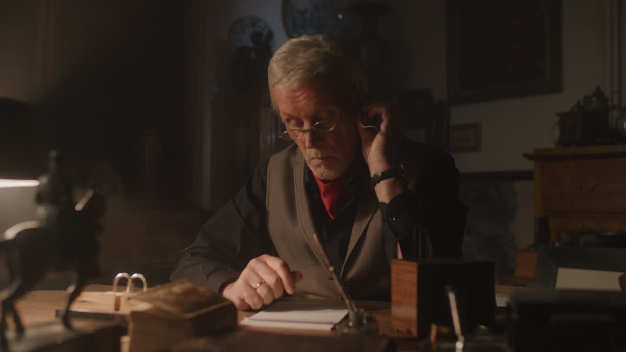 Older passionate man evaluates an old watch in his office at night