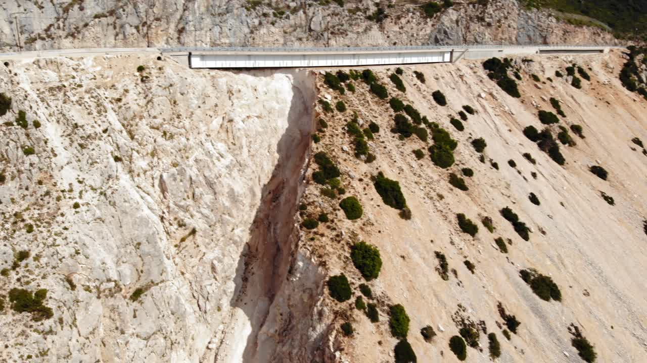 케팔로니아, 그리스의 미르토스 해변이 있는 거대한 균열이 있는 바위산의 해안 도로