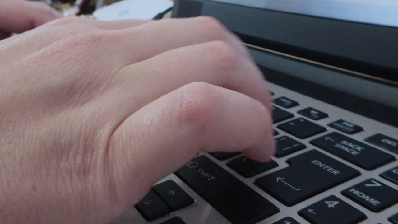 Front view of student's hands typing on a laptop keyboard. E-learning, research, or academic