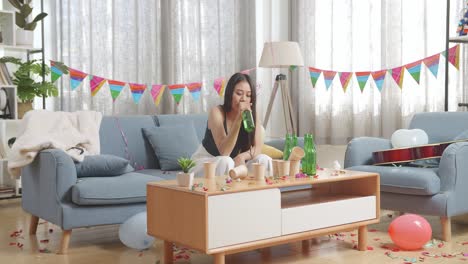 drunk asian woman sitting on a sofa and drinking alcohol while having a party alone at home