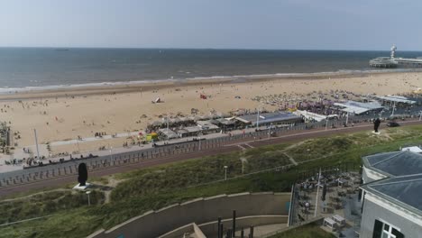 cámara lenta de drones de la playa de scheveningen con el muelle al fondo durante el clima cálido