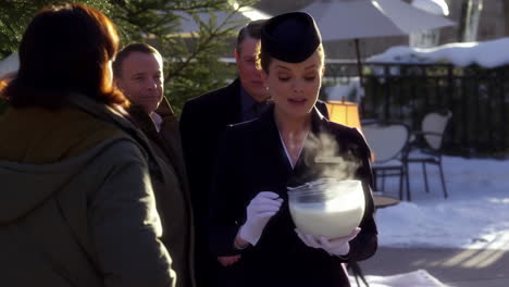 woman in uniform serves a steaming winter beverage outdoors