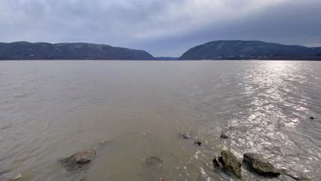 Lado-Pan-River-Beach-Hyper-Lapse-Durante-El-Invierno,-Con-Montañas-Distantes-Ligeramente-Cubiertas-De-Nieve-Y-Una-Costa-Rocosa