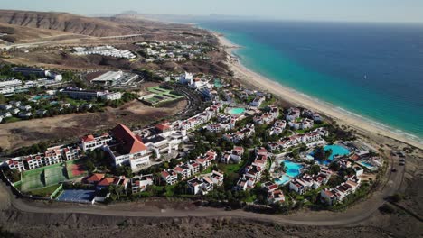 coastal resort in fuerteventura with hotels, pools, and the ocean, aerial view