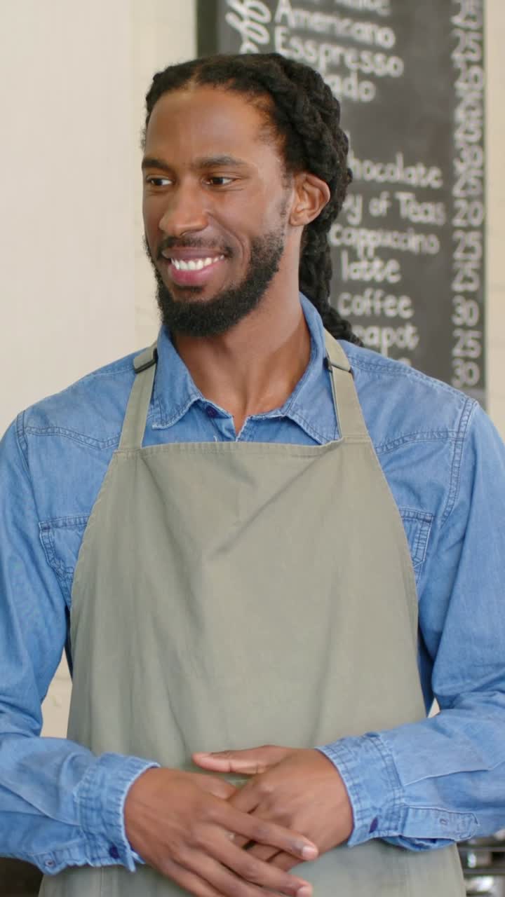 Vídeo vertical: Barista sorrindo, ouvindo e respondendo para anotar o pedido no balcão da cafeteria, com avental