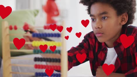animación de los iconos del corazón de las redes sociales sobre un niño biracial sonriente que usa ábaco