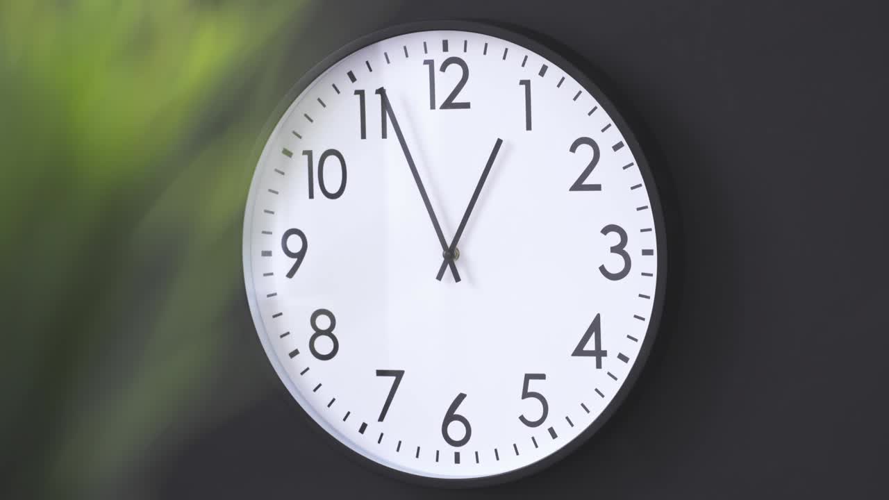 Simple clock hanging on black wall close up