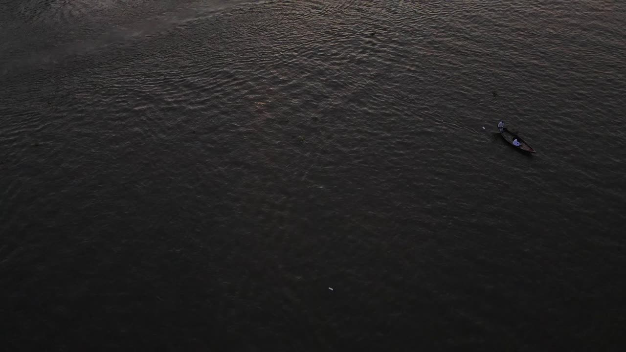 Aerial: view of a polluted river with moving boat at evening