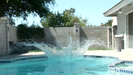 A-man-wearing-fins-and-a-snorkel-jumps-off-of-a-diving-board-into-a-pool