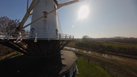 fpv drone shot of a stationary traditional white windmill in the netherlands against a blue sky