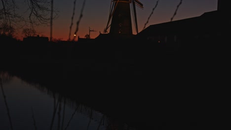 tilt up from river to a beautiful classic windmill at magic hour in a typical dutch landscape