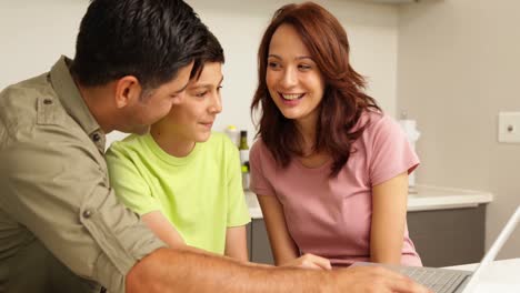 parents using laptop with their cute son