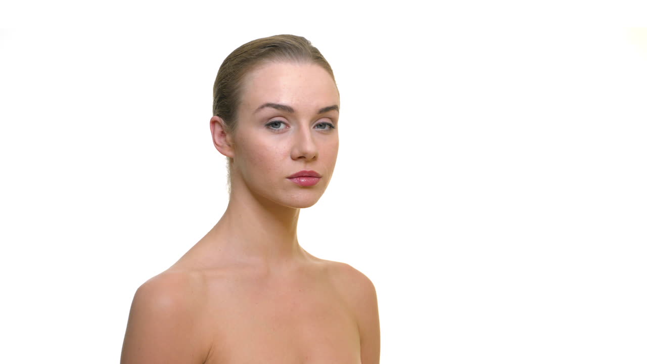 joven hermosa modelo desnuda en el estudio mirando seriamente a la cámara, sobre un fondo blanco