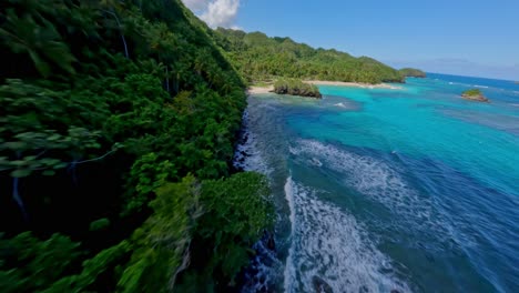 FPV-Drohne-Rast-Entlang-Der-Küste-Mit-Palmen-Zu-Einem-Sonnigen,-Exotischen-Sandstrand