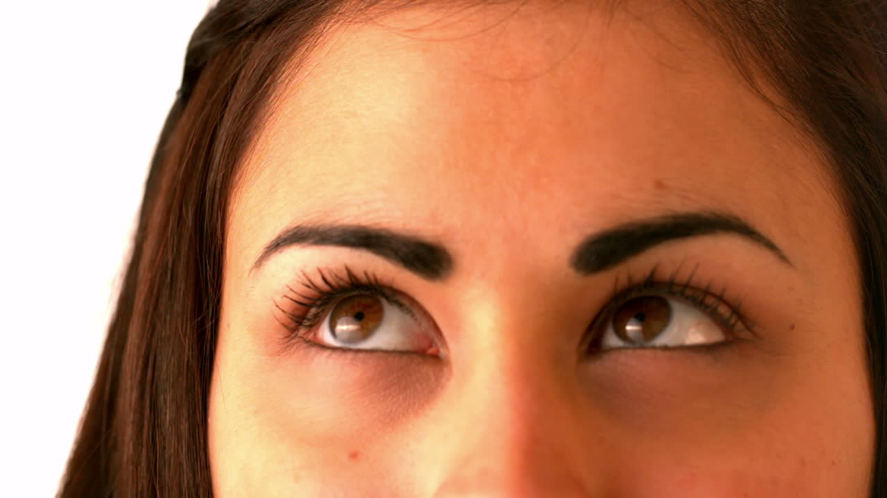 una morena muy bonita mirando hacia arriba pensativamente.