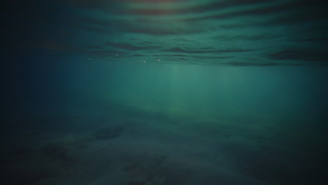 underwater view of mystic turquoise green rays of light on sandy water