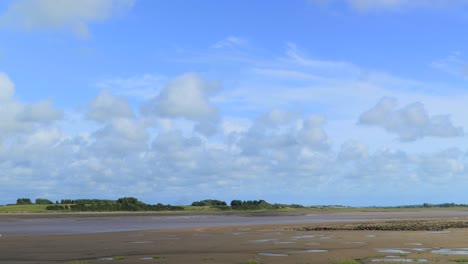 fluffy clouds blowing across river estuary with cloud shadows, time lapse 60x at river wyre estuary, fleetwood, lancashire, england, uk