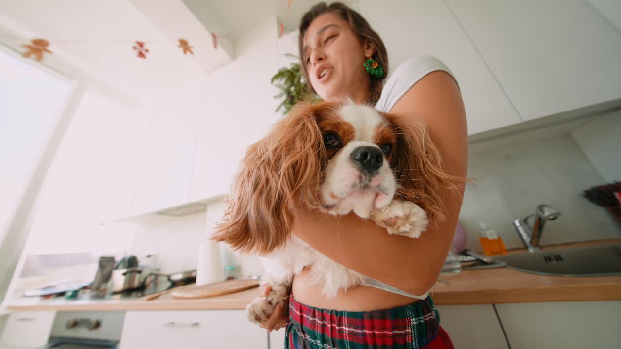 Woman hugging her Cavalier King Charles Spaniel in the kitchen