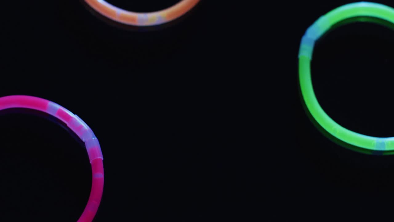 animación de múltiples palos de brillo de neón coloridos sobre fondo negro con espacio de copia