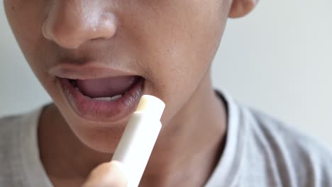 young man applying moisturising lip balm on lips