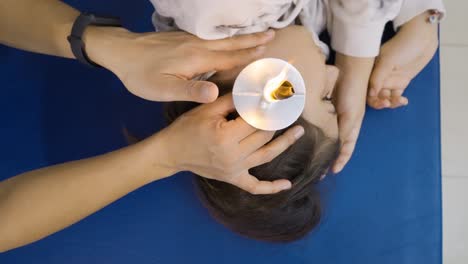 Top-down-view-of-a-young-girl-during-an-ear-candling-session