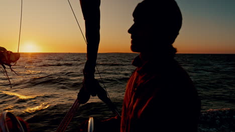 vela, hombre y puesta de sol en un barco