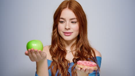 doubt female person making a decision in studio. girl choosing doughnut indoors