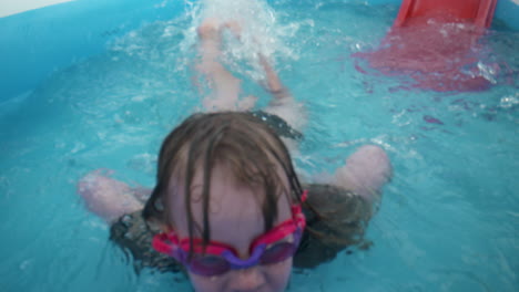 happy little girl swims toward the camera