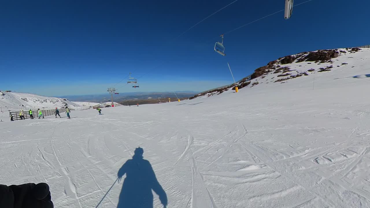 Sci 4K POV su una pista soleggiata in Sierra Nevada, Spagna, con azione ad alta velocità, neve bianca e scintillante e il cielo azzurro brillante dell'Andalusia.