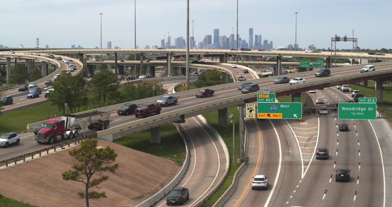 A striking aerial view of downtown Houston captured from above the I-45 South freeway, with the downtown skyline serving as the dramatic backdrop
